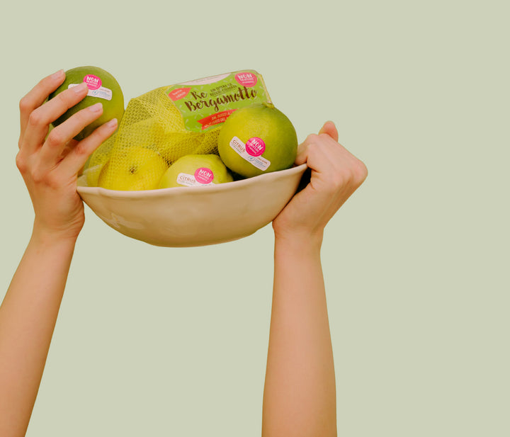 mani che reggono confezioni di bergamotti Citrus di colore verde